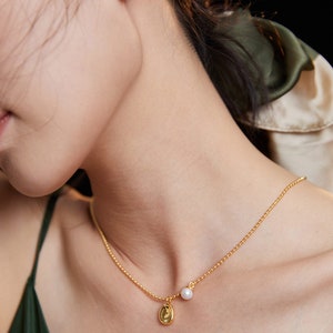 May include: A gold chain necklace with a small gold pendant and a single white pearl charm.
