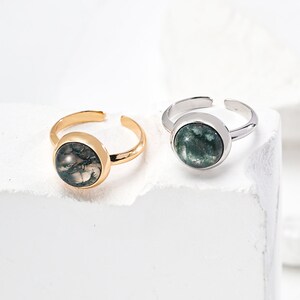May include: Two adjustable rings with green agate stones. The ring on the left has a gold band and the ring on the right has a silver band.