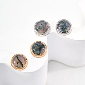 May include: Three pairs of earrings with a silver and gold setting. Each earring features a round, green and gray agate stone.