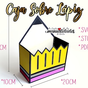 Puede incluir: Una caja amarilla con forma de lápiz con detalles en blanco y negro. La caja mide 26 cm de alto, 20 cm de ancho y 10 cm de profundidad. La caja está etiquetada con "Caja Sobre Lapiz" y "manualidades de Dorita".