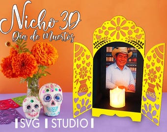 Puede incluir: Un nicho 3D decorativo amarillo para el Día de Muertos, con una foto, una vela encendida y un ramo de caléndulas. Dos calaveras de azúcar decoradas y el texto "Nicho 3D Dia de Muertos" también son visibles. La imagen tiene un fondo naranja.