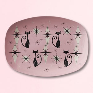 May include: A pink oval serving platter with a retro design featuring black cats and white stars.