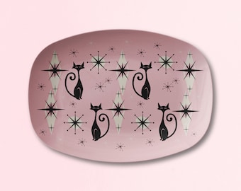 May include: A pink oval serving platter with a retro design featuring black cats and white stars.
