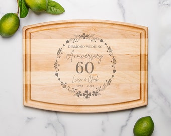 May include: A wooden cutting board with a decorative engraved design celebrating a 60th anniversary. The design features a floral wreath with the text "Diamond Wedding Anniversary 60 Luisa & Clark 1964 - 2024".