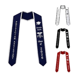 May include: Graduation sashes in navy blue, white, black, and red. Each sash features the text "Physician Assistant" and "Class of 2026." One sash is personalized with a name and PA symbol. The sashes are for a graduation ceremony.