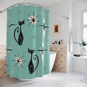 May include: A teal shower curtain with a retro design featuring black cats and white starbursts. The shower curtain is hanging in a bathroom with a white tub and a white tiled wall.
