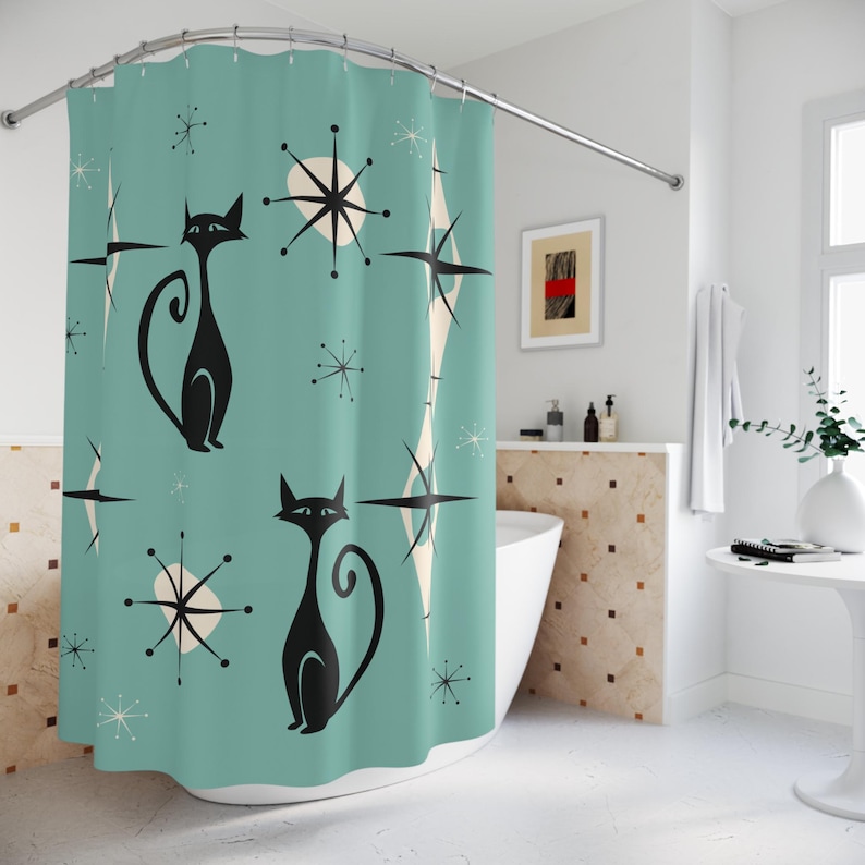 May include: A teal shower curtain with a retro design featuring black cats and white starbursts. The shower curtain is hanging in a bathroom with a white tub and a white tiled wall.