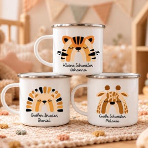 May include: Three white enamel mugs with silver rims, each featuring a colorful animal illustration shaped like a rainbow. The top mug shows a tiger with the text "Kleine Schwester Johanna". The bottom mugs show a lion and giraffe with names.
