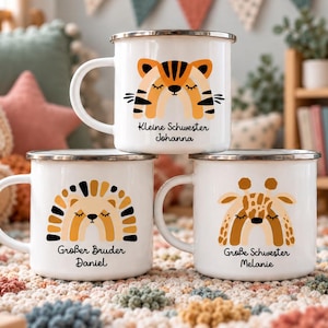 May include: Three white enamel mugs featuring animal illustrations and text. The top mug shows a tiger with "Kleine Schwester Johanna". The bottom left mug shows a lion with "Gro&szlig;er Bruder Daniel". The bottom right mug shows a giraffe with "Gro&szlig;e Schwester Melanie".