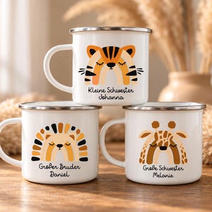 May include: Three white enamel mugs with silver rims, each featuring a colorful animal illustration and text. The top mug shows a tiger with "Kleine Schwester Johanna". The bottom left shows a hedgehog with "Gro&szlig;er Bruder Daniel" and the bottom right a giraffe with "Gro&szlig;e Schwester Melanie".