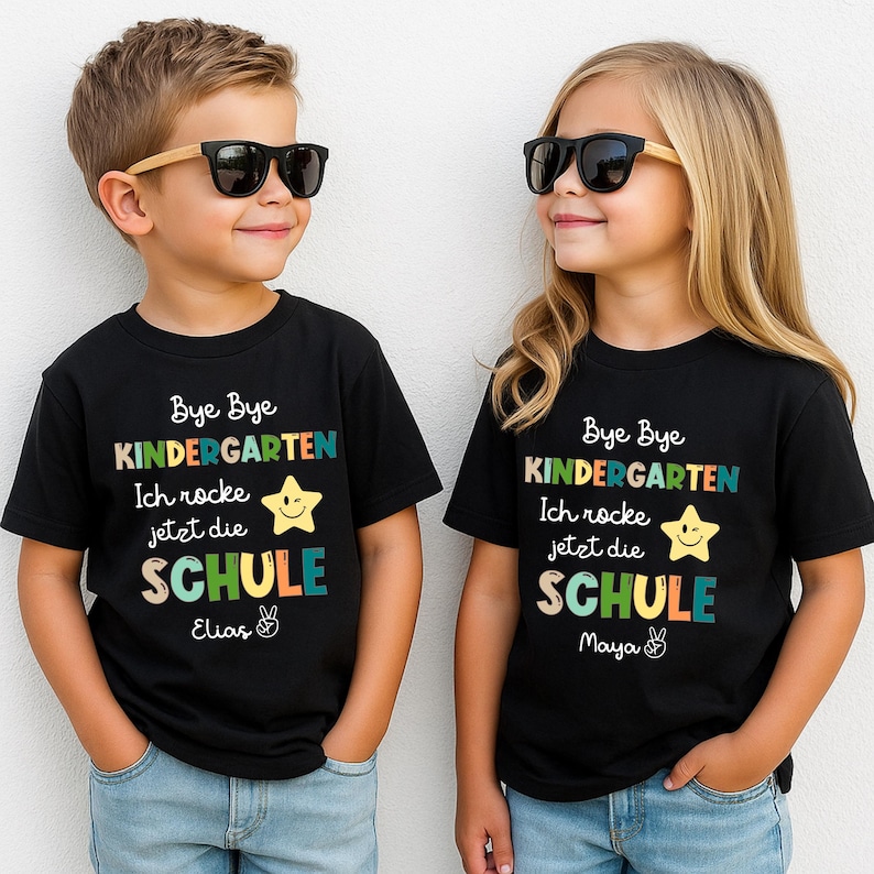 Puede incluir: Dos ni&ntilde;os con camisetas negras con el texto "Bye Bye Kindergarten" y "Ich rocke jetzt die SCHULE". Las camisetas tienen un gr&aacute;fico de estrella y los nombres "Elias" y "Maya". Ambos ni&ntilde;os llevan gafas de sol.
