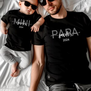 May include: A black t-shirt with the text "PARA jacobs 2024" and a smaller black t-shirt with the text "MINI jacobs 2024".