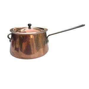 May include: A polished copper saucepan with a rounded body, a matching lid featuring a small black knob, a long metal handle extending from the side, and a small secondary loop handle on the opposite side, showcasing a warm metallic finish.