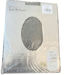 May include: A pair of Pierre Mantoux tights in a black and white herringbone pattern, packaged in a clear plastic sleeve. The packaging features a size chart, a barcode label, and the text Haute Couture des Jambes printed at the bottom.
