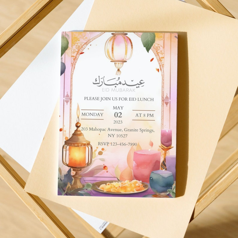 May include: An invitation card with a watercolor design featuring a lantern, a plate of food, and a glass of juice. The card is decorated with a pink and orange gradient background and has the text "Eid Mubarak" in Arabic script. The invitation is for an Eid lunch on Monday, May 02, 2023, at 8 PM. The address is 203 Mahopac Avenue, Granite Springs, NY 10527. The RSVP number is 123-456-7890.