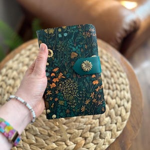 May include: A white ceramic mug with a black handle and the text "But First, Coffee" in a bold, black font. The mug is set against a neutral background, highlighting its simple design.