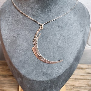 Peut inclure: Un collier en argent avec un pendentif en forme de croissant de lune. Le pendentif est détaillé avec un motif d'arbre.