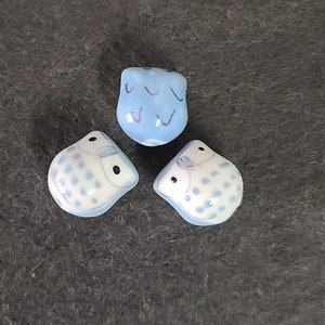 Könnte beinhalten: Drei Keramik-Eulenfiguren. Eine Eule ist blau mit einem weißen Muster, die anderen beiden Eulen sind weiß mit blauen Punkten.