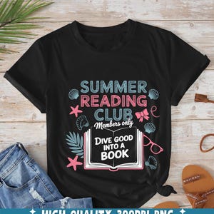 Op de afbeelding: Zwart T-shirt met een grafisch ontwerp voor een zomerleesclub. Het ontwerp bevat de tekst "Summer Reading Club Members Only" en "Dive Good Into a Book". Het ontwerp bevat ook schelpen, zeesterren en een boek.
