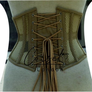 May include: A beige corset with a mesh panel and brown laces. The corset is tied at the back with long brown laces. The text "Corsets London" is visible on the bottom of the corset.