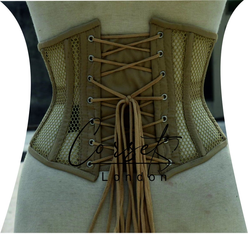 May include: A beige corset with a mesh panel and brown laces. The corset is tied at the back with long brown laces. The text "Corsets London" is visible on the bottom of the corset.