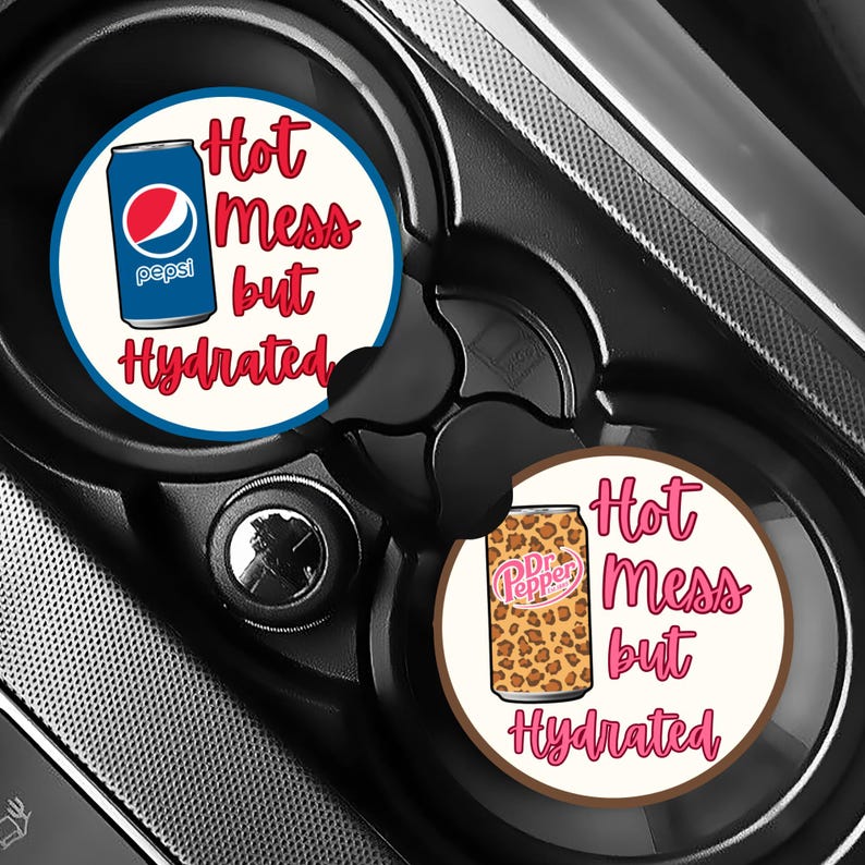 May include: Two car coasters with a white background and the text "Hot Mess but Hydrated" in red script. One coaster features a Pepsi can, the other a Dr. Pepper can with a leopard print design.