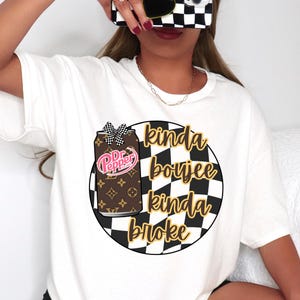 Könnte beinhalten: Weißes T-Shirt mit einer Grafik einer Dr. Pepper-Dose mit Schleife, vor einem schwarz-weiß karierten Kreis. Der Text "kinda boujee kinda broke" ist in goldener Schrift geschrieben.