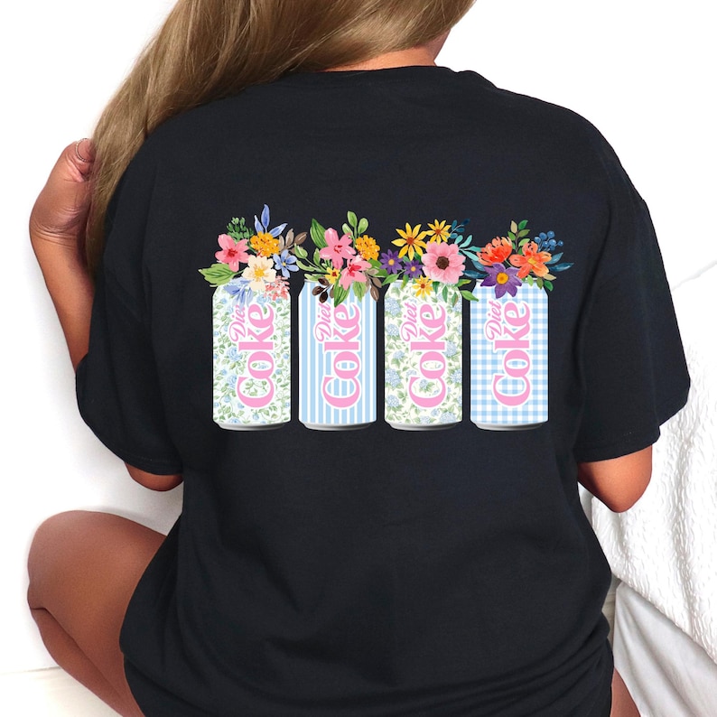 K&ouml;nnte beinhalten: Schwarzes T-Shirt mit einem Design von vier Diet Coke-Dosen, die jeweils mit Blumen geschm&uuml;ckt sind. Die Dosen zeigen verschiedene Muster: floral, blaue Streifen, floral und blaues Vichy. Die Worte "Diet Coke" sind in Pink.