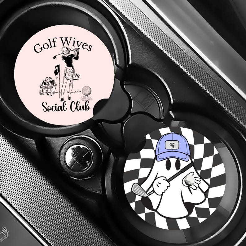 Puede incluir: Dos posavasos para coche con dise&ntilde;os de golf. Uno es de color rosa claro con una ilustraci&oacute;n vintage de una golfista y el texto "Golf Wives Social Club". El otro presenta un fantasma de dibujos animados con un palo de golf y un fondo a cuadros.