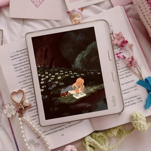 Può includere: Un e-reader Kobo bianco che mostra l'illustrazione di un personaggio biondo che legge un libro in un ambiente boschivo scuro. Il dispositivo presenta due pulsanti verticali sul lato destro ed è posizionato sopra un libro aperto con testo in russo.