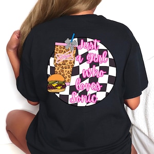 Op de afbeelding: Zwart T-shirt met een afbeelding van een Sonic-drankje, een hamburger en de tekst "Just a girl who loves Sonic" in roze. De drank heeft een luipaardprint en een geblokte rietje.