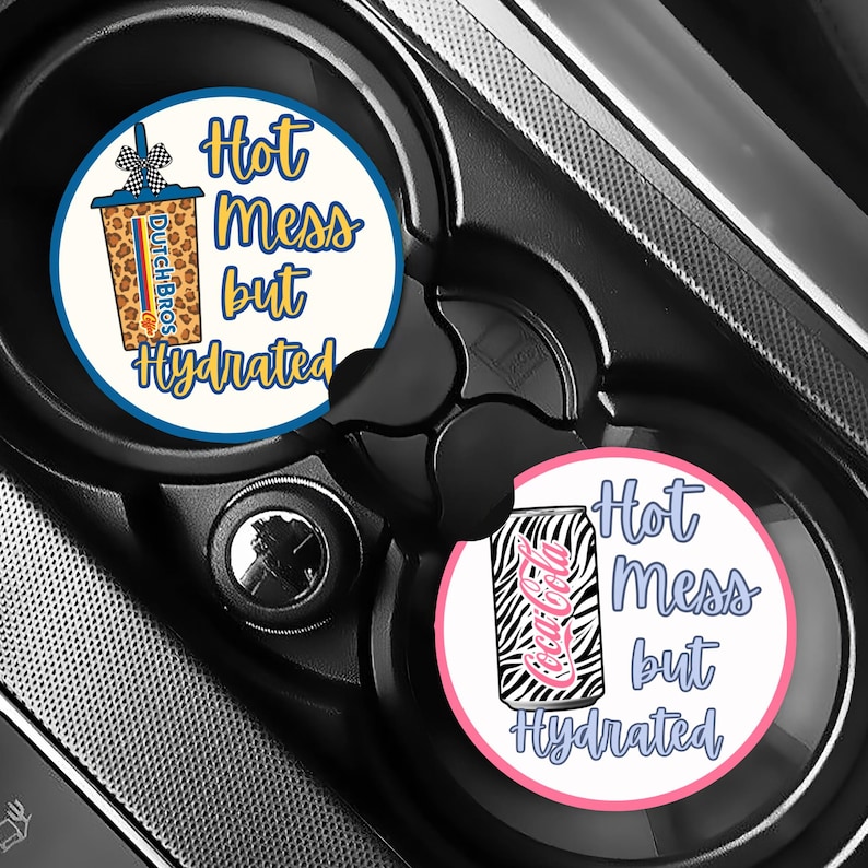 May include: Two car coasters with the text "Hot Mess but Hydrated." One coaster features a Dutch Bros coffee cup design, and the other has a Coca-Cola can with a zebra print.