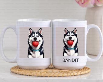 May include: Two white ceramic mugs with a black and white husky dog illustration holding a red ball in its mouth. The mug on the right has the word "BANDIT" printed on it.
