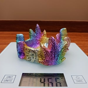 Puede incluir: Un cenicero de metal con forma de hoja, con reflejos arcoíris, sobre una báscula de cocina digital que marca 4,66 gramos.