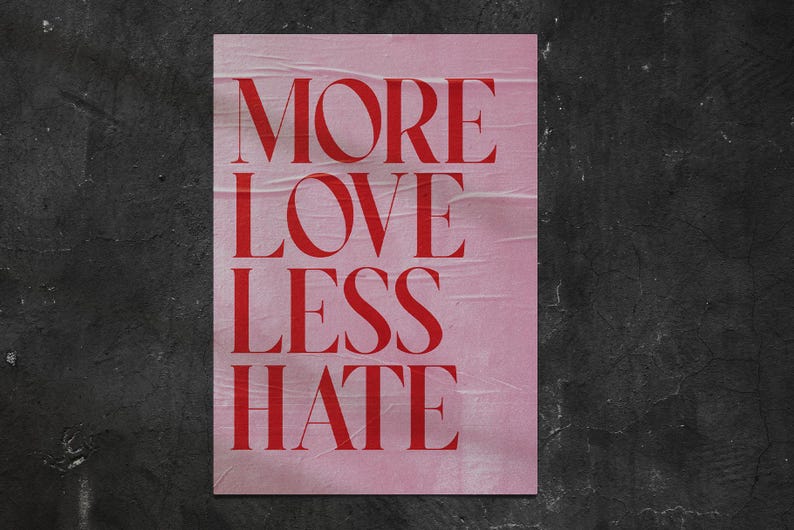 May include: A pink poster with the words "MORE LOVE LESS HATE" in bold red letters. The poster has a distressed, wrinkled texture and is set against a dark, textured background.
