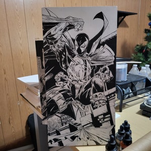 May include: Black and white illustration of a comic book character, Spawn, in a dynamic pose. He is wearing a cape and a mask, and he is holding a chain in his hand. The background is a cityscape.