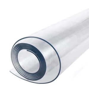 May include: A rolled-up, clear plastic sheet against a white background. The edges of the roll are visible, showing the layers of the material. The plastic appears transparent, with a slight sheen.