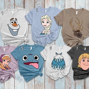 May include: A collection of seven short-sleeved t-shirts featuring cartoon character designs. The shirts are in various colors, including white, light blue, brown, purple, and charcoal. Each shirt displays a different character face, perfect for fans of animated movies.