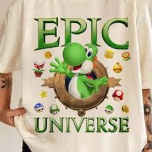 May include: White t-shirt with a green Yoshi character from the Super Mario video game series. The shirt has the text "EPIC UNIVERSE" printed on it.
