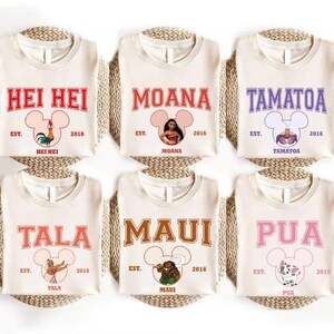 May include: Six cream-colored t-shirts with various character names in bold lettering. Each shirt features a Mickey Mouse head design and the text "EST. 2016". The names include Hei Hei, Moana, Tamatoa, Tala, Maui, and Pua.