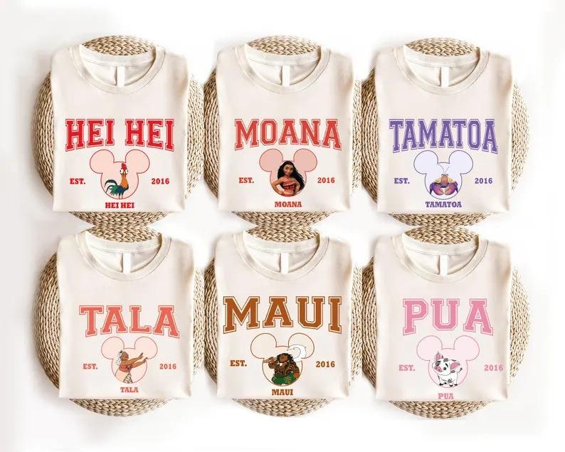 May include: Six cream-colored t-shirts with various character names in bold lettering. Each shirt features a Mickey Mouse head design and the text "EST. 2016". The names include Hei Hei, Moana, Tamatoa, Tala, Maui, and Pua.