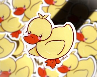 May include: A yellow rubber duck with a red beak and orange feet. The duck has a cute cartoon face with big eyes and a small smile. The duck is surrounded by other rubber ducks.