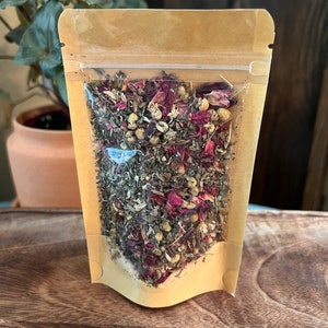 May include: A brown paper pouch with a clear plastic window, filled with a blend of dried herbs and rose petals.