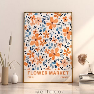 May include: A framed print with a floral pattern in shades of orange, blue, and white. The print has the text "FLOWER MARKET" with "PARIS" and "FRANCE" below it.