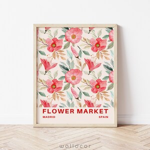May include: A framed print with a watercolor floral pattern in shades of pink and green. The print has the text "FLOWER MARKET" in red, with "MADRID" and "SPAIN" below it.