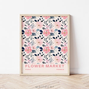 May include: A framed print with a floral pattern in shades of pink and blue. The print has the text "FLOWER MARKET" in pink letters, with "PARIS" and "FRANCE" in smaller black letters below.