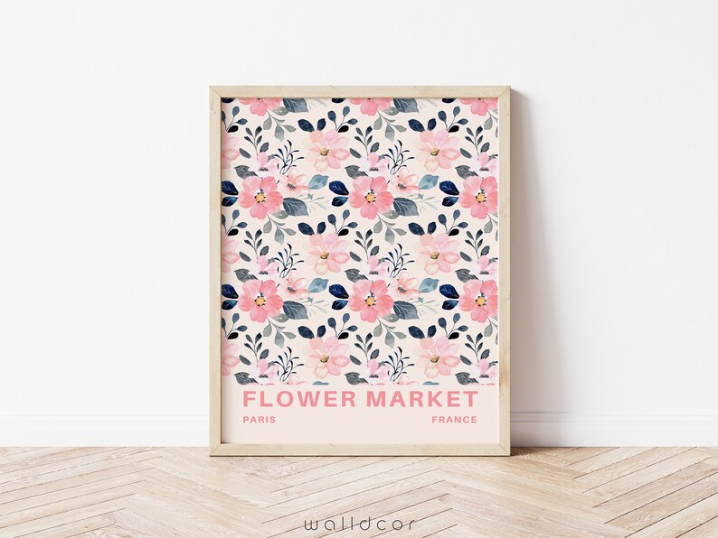 May include: A framed print with a floral pattern in shades of pink and blue. The print has the text "FLOWER MARKET" in pink letters, with "PARIS" and "FRANCE" in smaller black letters below.