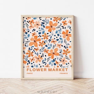 May include: A framed print with a floral pattern in shades of orange, blue, and white. The print has the text "FLOWER MARKET" in orange, "PARIS" in black, and "FRANCE" in black.