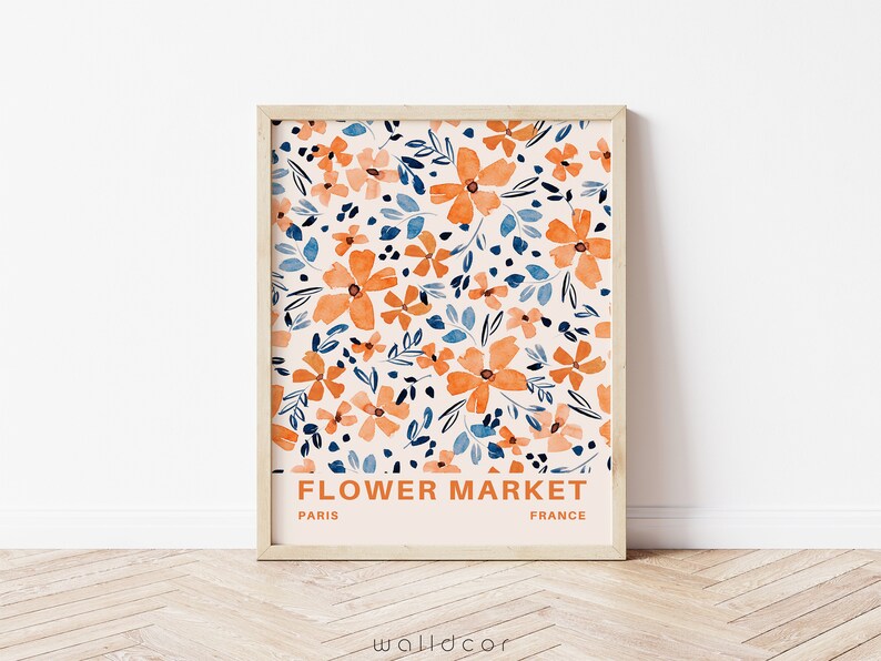 May include: A framed print with a floral pattern in shades of orange, blue, and white. The print has the text "FLOWER MARKET" in orange, "PARIS" in black, and "FRANCE" in black.