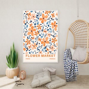 May include: A framed print with a floral pattern in shades of orange and blue. The print has the text "FLOWER MARKET" with "PARIS" and "FRANCE" below it.
